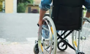 Osoba na wózku inwalidzkim, która może skorzystać z programu 500 plus dla niepełnosprawnych, porusza się po chodniku.
