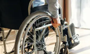 Osoba w wózku inwalidzkim chwyta za koło. Orzeczenie o niepełnosprawności otwiera drogę do wsparcia i możliwości.