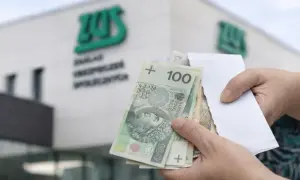 Ręce trzymają polskie banknoty przed budynkiem ZUS. Wypłata 14 emerytury wreszcie nadeszła.