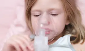 Mała dziewczynka z maską inhalatora na twarzy. Pomaga jej to w leczeniu kaszlu.