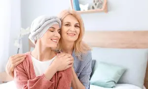 Dwie kobiety, jedna w chuście na głowie, uśmiechają się do siebie. Wsparcie i nadzieja w trudnych chwilach, gdy liczy się leczenie paliatywne.