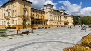 Elegancki budynek sanatorium, plac z ławkami i spacerujący ludzie. Dowiedz się o nowe zasady wyjazdu do sanatorium na NFZ.