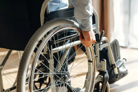 Osoba w wózku inwalidzkim chwyta za koło. Orzeczenie o niepełnosprawności otwiera drogę do wsparcia i możliwości.