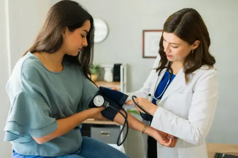 Lekarka zakłada mankiet do pomiaru ciśnienia pacjentce. To ważny etap diagnostyki, często poprzedzający skierowanie do specjalisty.