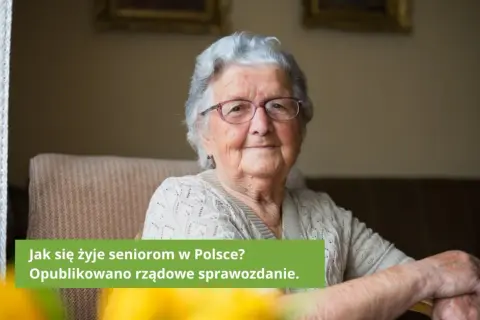 Uśmiechnięta starsza kobieta w okularach siedzi w fotelu.