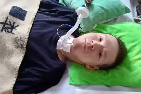 Chłopiec z chorobą DMD leży w łóżku, podłączony do respiratora.
