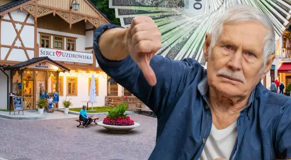 Starszy pan pokazuje kciuk w dół, trzymając stos banknotów. W tle budynek "Serce Uzdrowiska" w Szczawnicy.