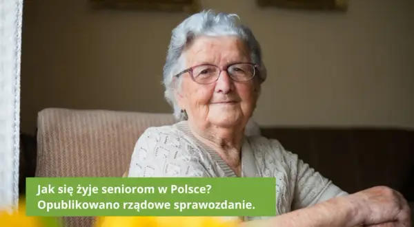 Uśmiechnięta starsza kobieta w okularach siedzi w fotelu.