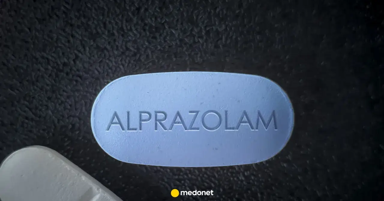 Niebieska tabletka z napisem ALPRAZOLAM, często stosowana jako lek na lęk, leży obok białej tabletki.