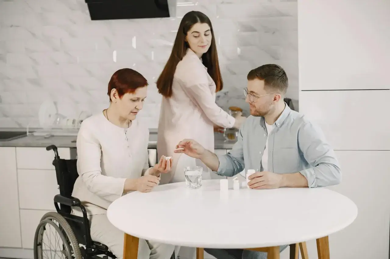 Rodzina wspiera starszą panią na wózku, podając jej leki psychotropowe.